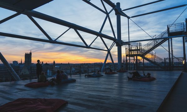 编辑在整理体育资讯平台版本更新记录的桌面场景，桌上摆放笔记本与打印文档